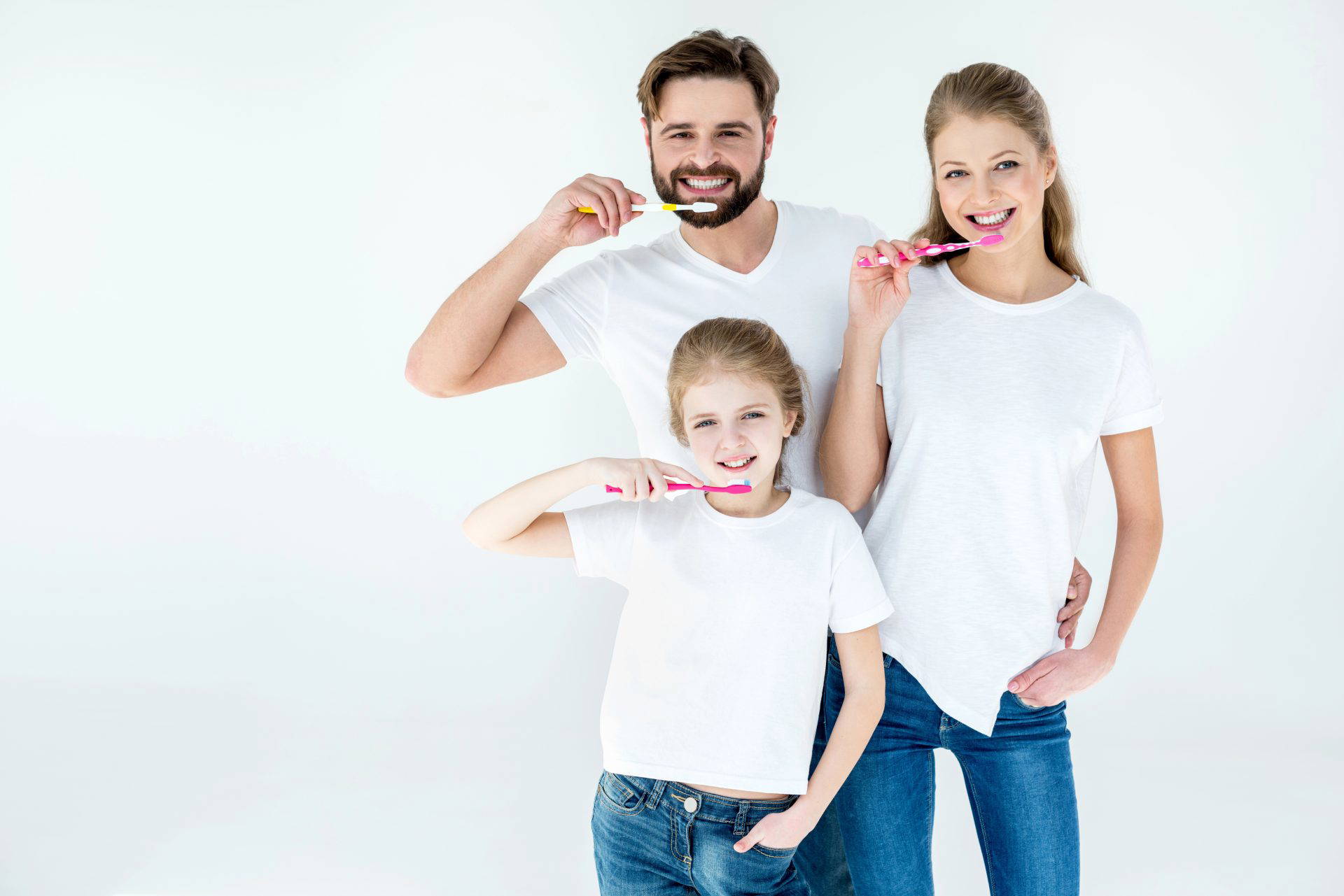 Father and daughters smiling while brushing their teeth together