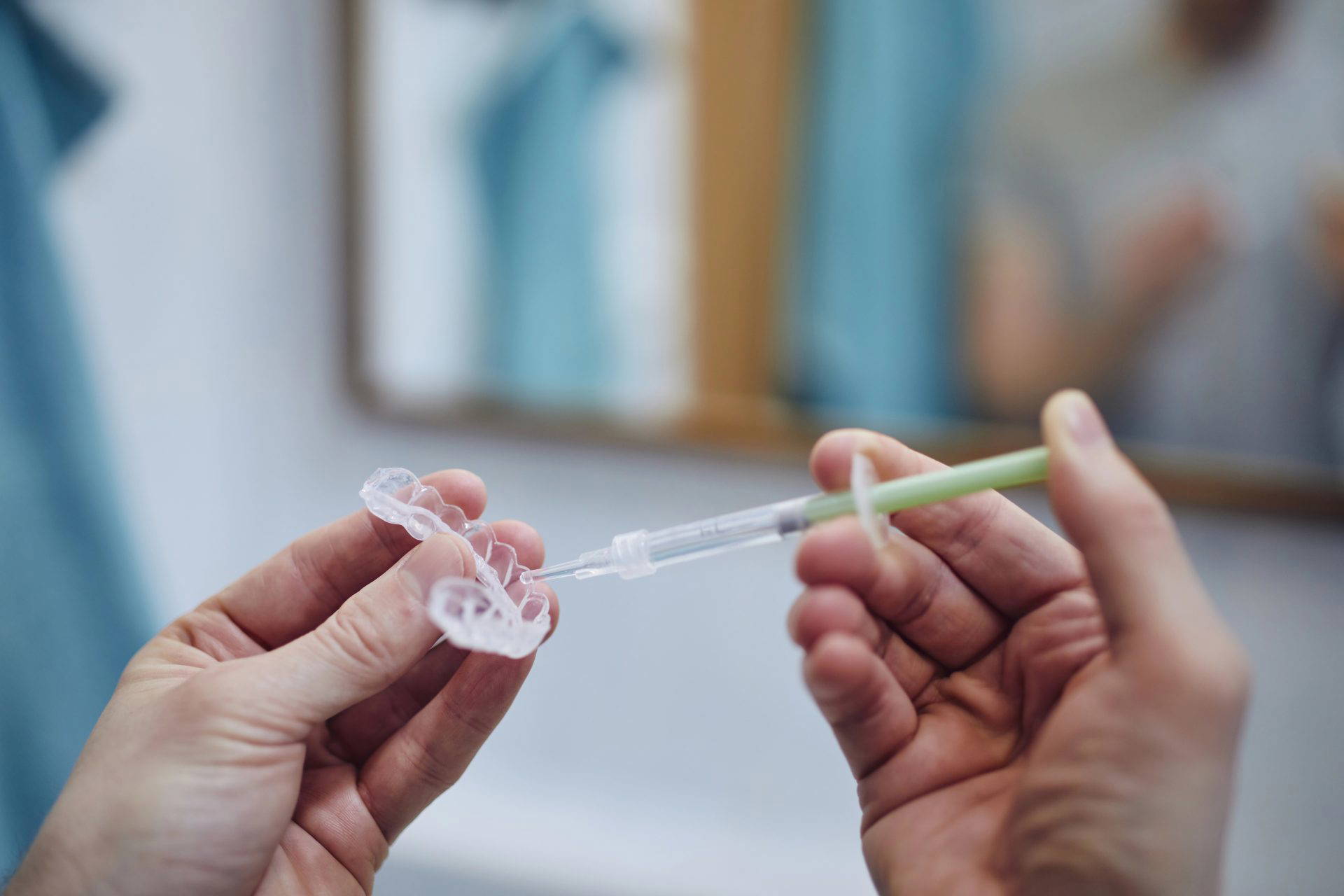 An image of a dentist filling a mouth guard with whitening solution