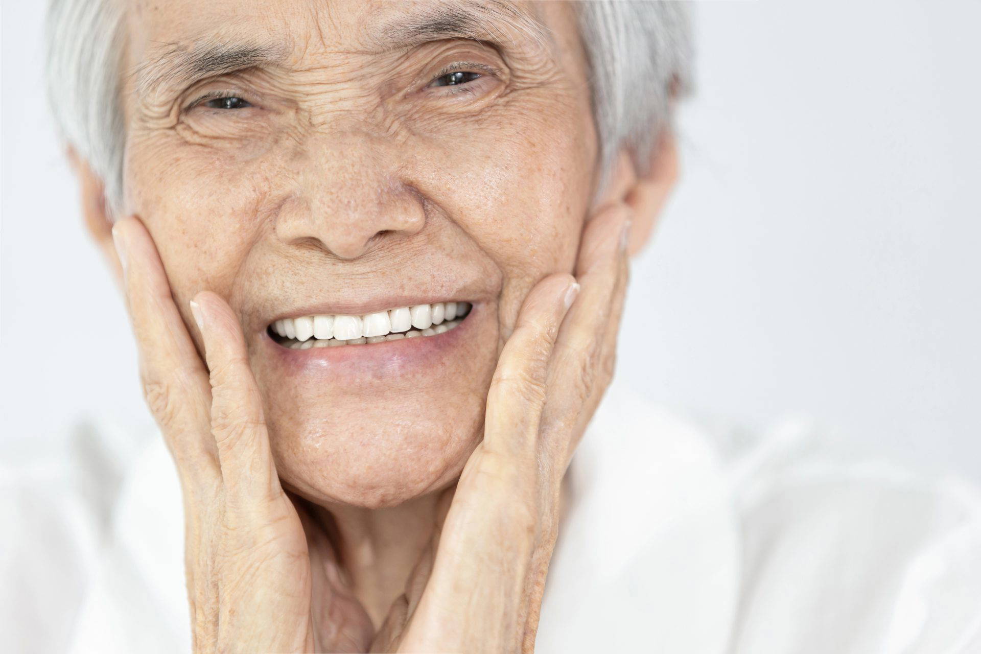 Elderly woman smiling happily with new dentures